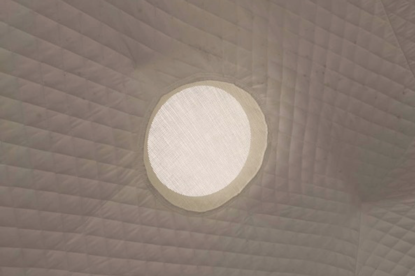 Alt text: &quot;Interior view of a geodesic dome featuring a porthole window, showcasing the quilted fabric design. Ideal for luxury glamping, backyard offices, or sustainable living spaces.&quot;